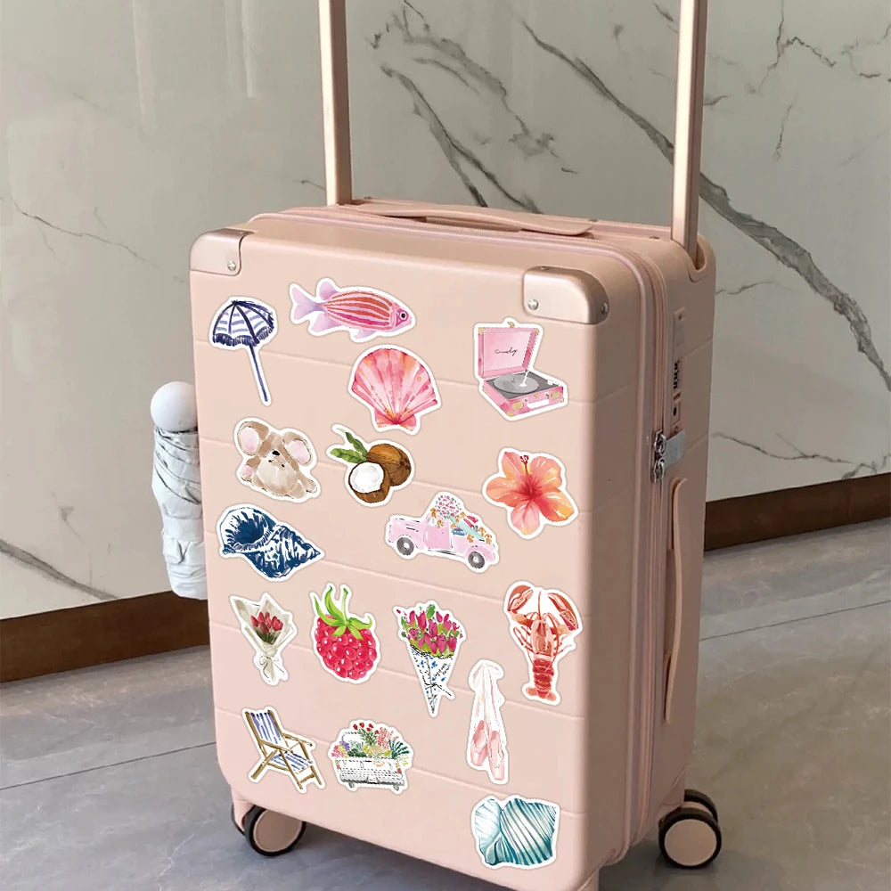 A pink rolling suitcase decorated with watercolor dairy stickers for crafting projects.