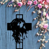 Black silhouette of a crown of thorns cross on light blue wooden background with pink and white floral vines