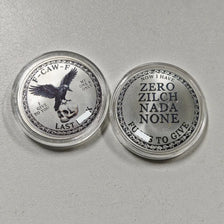 Two silver challenge coins featuring a crow and skull design, labeled with text like Now I Have Zero Zilch Nada None and Last