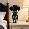 A black gothic skull resin decorative vase sits on a light wooden nightstand next to a dark wooden bed frame.