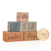 A stack of wooden baby milestone cards showing the numbers 2, 5, and 8 with an Easter theme.