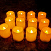 A row of glowing yellow LED flickering candles arranged on a dark surface.