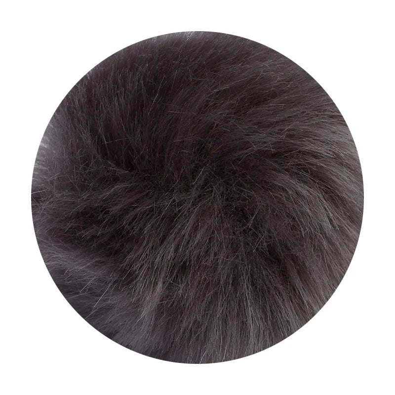 A round pom pom made of black faux fur attached to a silver chain.