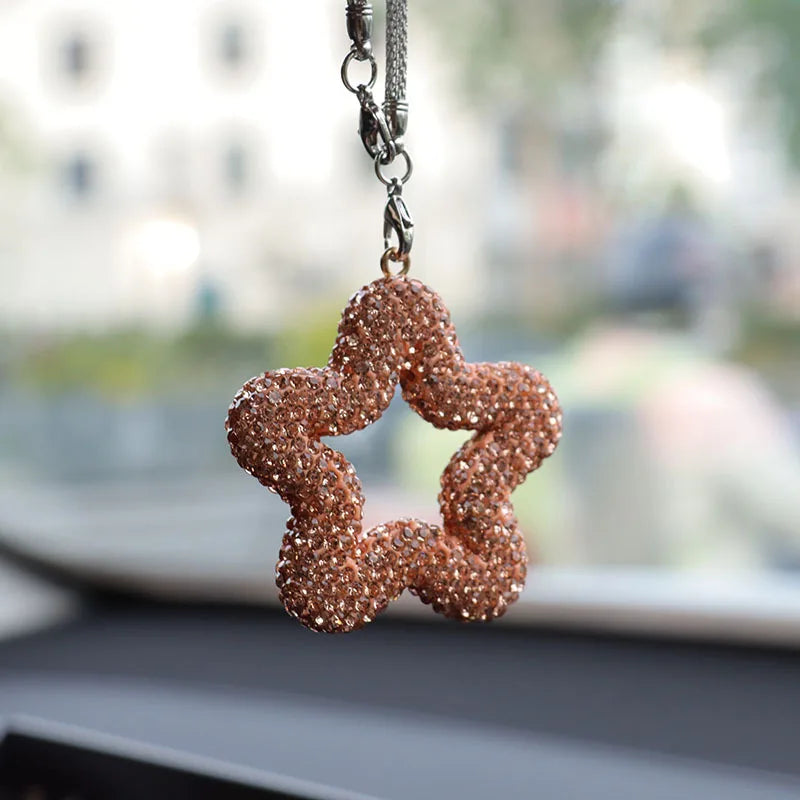 A sparkling, rose gold rhinestone star charm hanging from a silver chain.