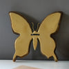 Artisan butterfly wall mirror with an antique gold frame mounted on a gray wall.