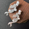 Silver vintage marine life brooch pin set featuring a leaping fish and pearl accents on a wooden background