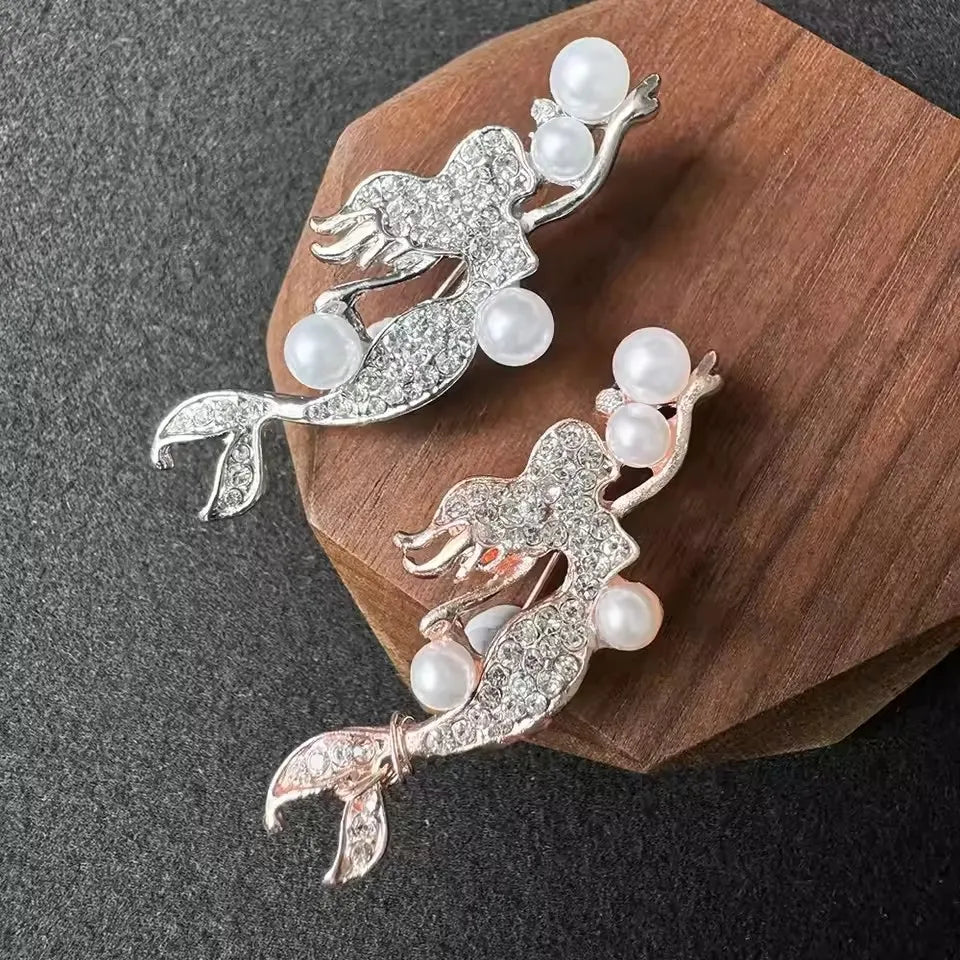 Silver vintage marine life brooch pin set featuring a leaping fish and pearl accents on a wooden background