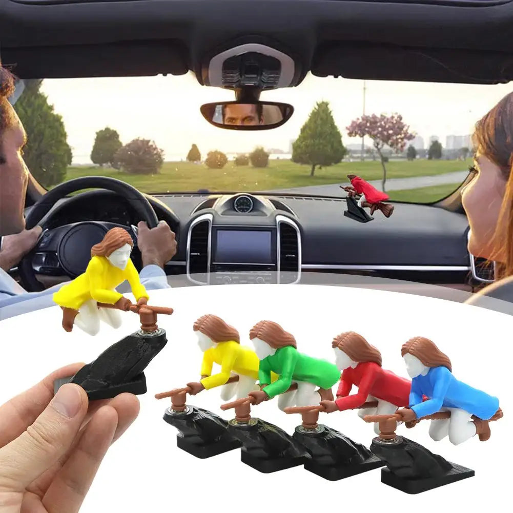 A set of witch and wizard flying carriage dashboard decor figures in various colors are shown being held by a hand.