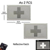 A rectangular reflective patch with a dark gray cross design and a loop for attachment.