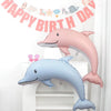 Pink and blue foil balloons shaped like a dolphin, seashell, and mermaid tail for a birthday party