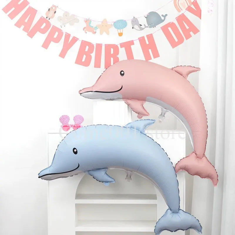 Pink and blue foil balloons shaped like a dolphin, seashell, and mermaid tail for a birthday party