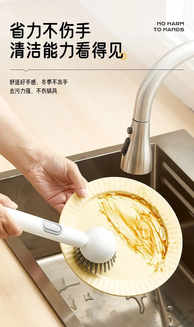 A hand is using an adjustable long-handled liquid washing brush to clean a plate in a kitchen sink.