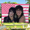 A photo of Jake Webber and Johnnie Guilbert tapestry wall hanging displayed in an outdoor setting.