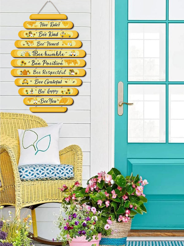 A wooden beehive rules sign with bee-themed text hangs on a white door frame next to a teal door.