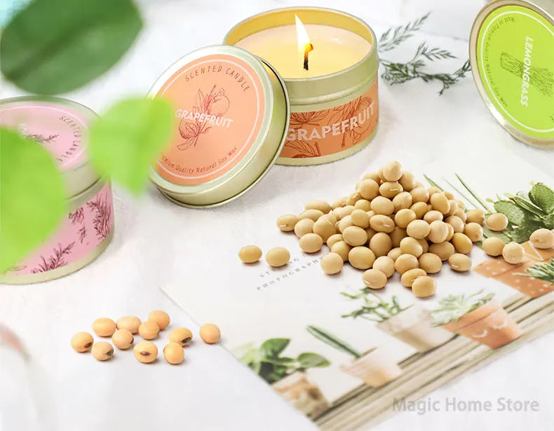 A natural soy wax travel candle in a gold tin with a lit wick and grapefruit scent surrounded by loose wax pellets.