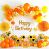 A colorful arrangement of orange and yellow latex balloons and flowers celebrating a happy birthday.