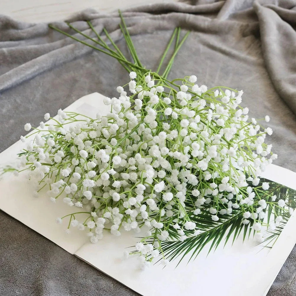 A bouquet of artificial white gypsophila flowers arranged on a white rectangular platter.