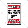 A vintage metal warning sign with text that reads WARNING REGISTERED GUN OWNER DO NOT TRESPASS