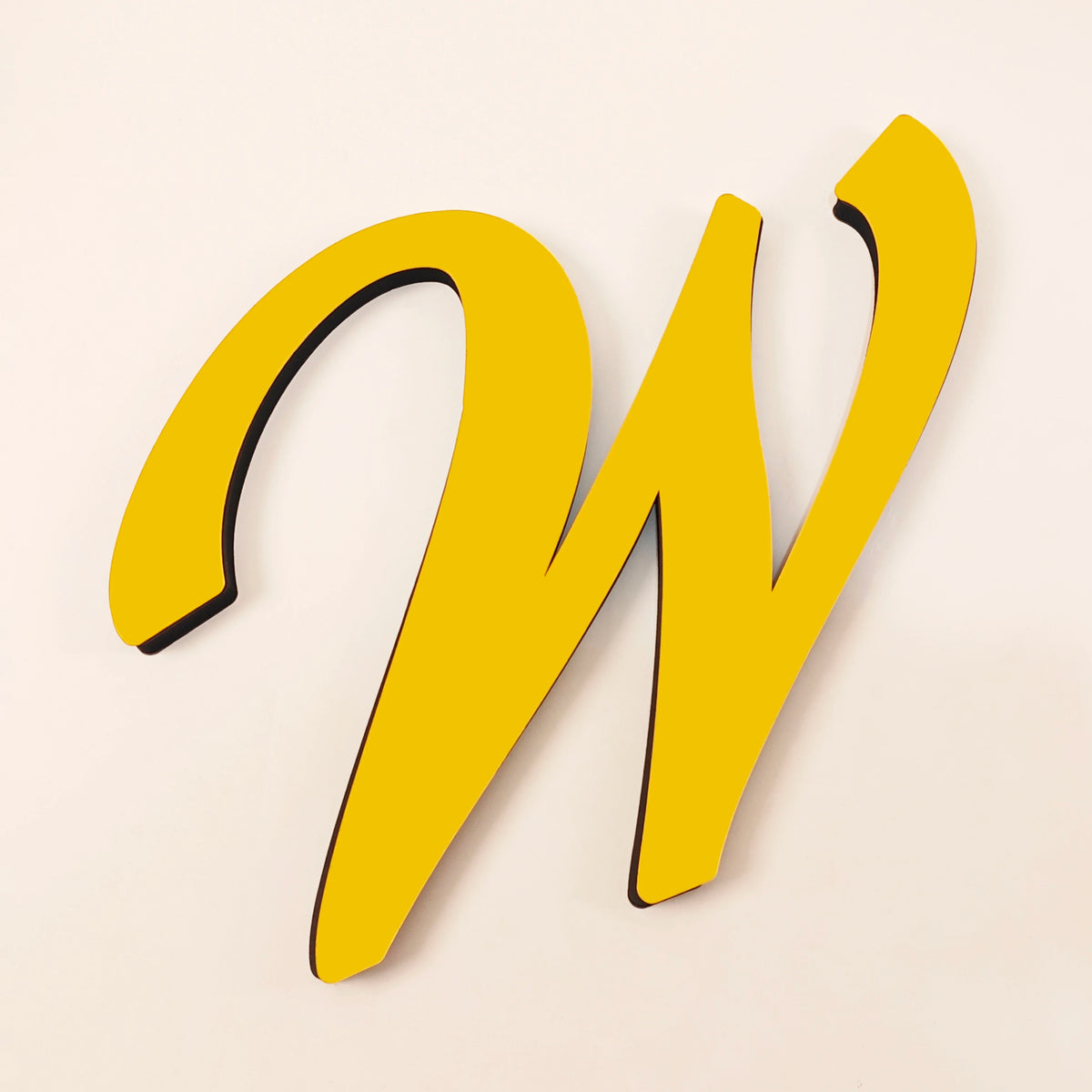 A yellow 3D acrylic letter W wall sticker against a light background.