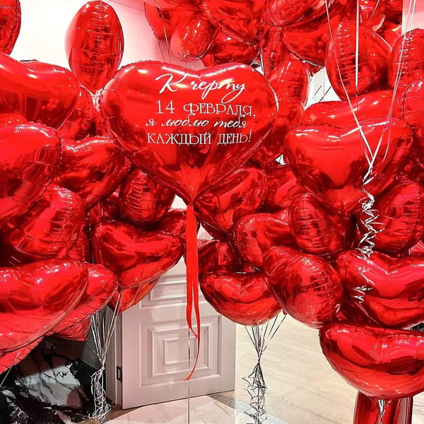 A dense arrangement of red heart-shaped foil balloons tied together with ribbons.
