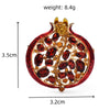 A red crystal pomegranate brooch pin featuring gold accents and ruby-colored stones.