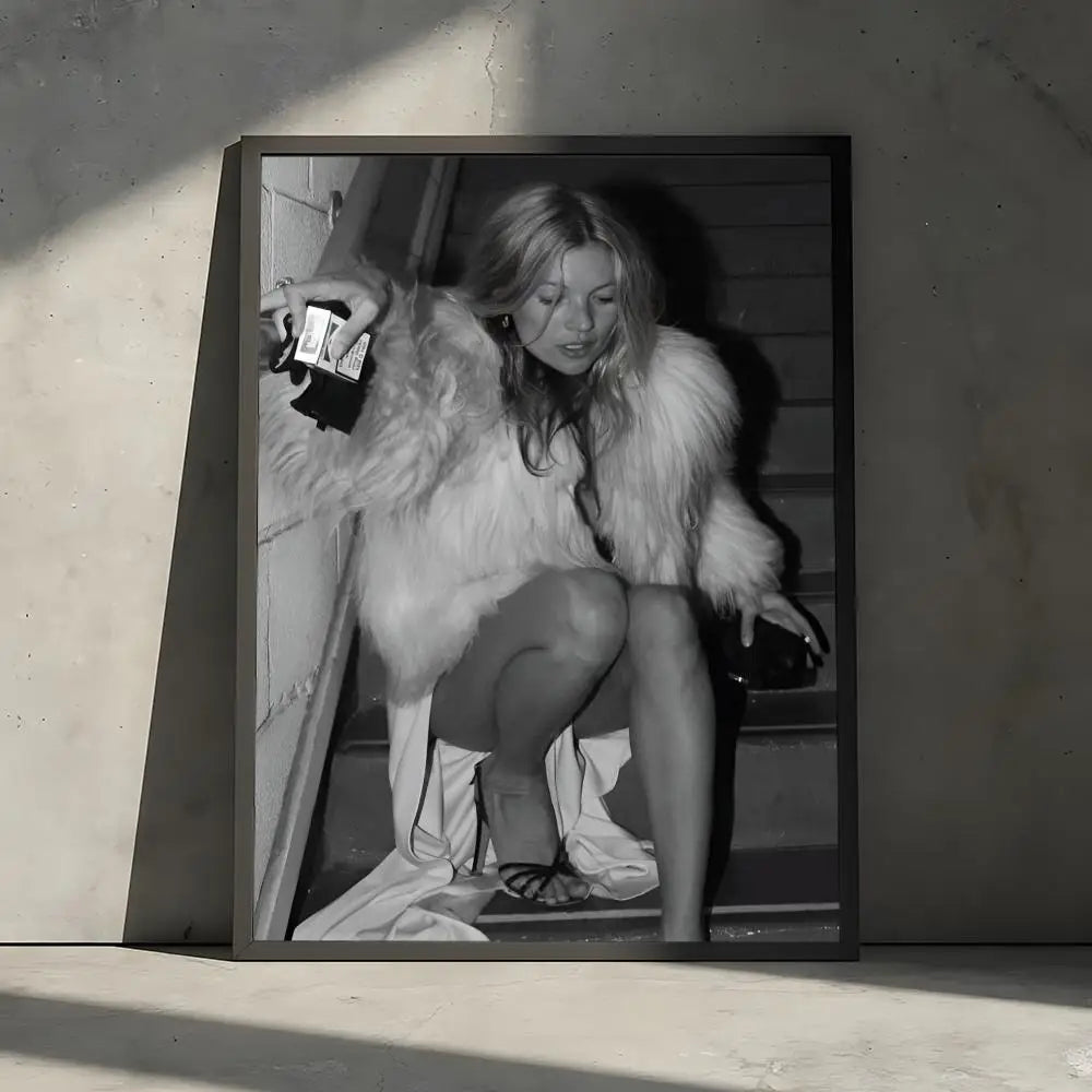 A black and white portrait of a woman with long hair wearing a fluffy white coat, displayed in a framed poster.