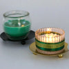 An elegant iron candle holder tray with gold accents holds a glowing green candle.