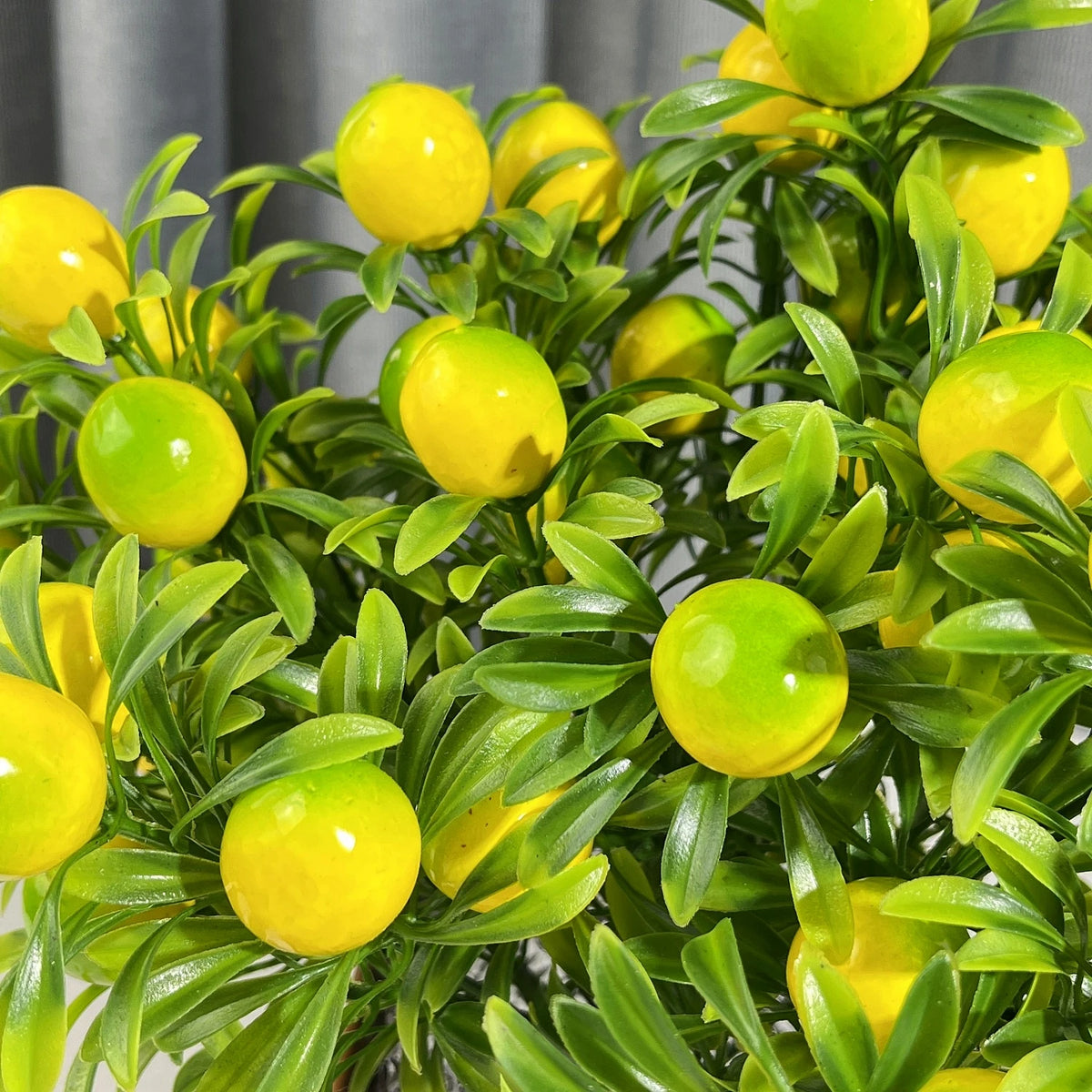 A close-up of a branch with four artificial lemon-green and yellow fruit stems.