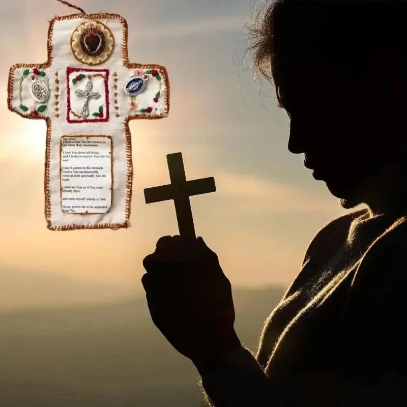 A silhouette of a person holding a hand-sewn silver prayer pocket decoration with a cross design against a sunset sky.