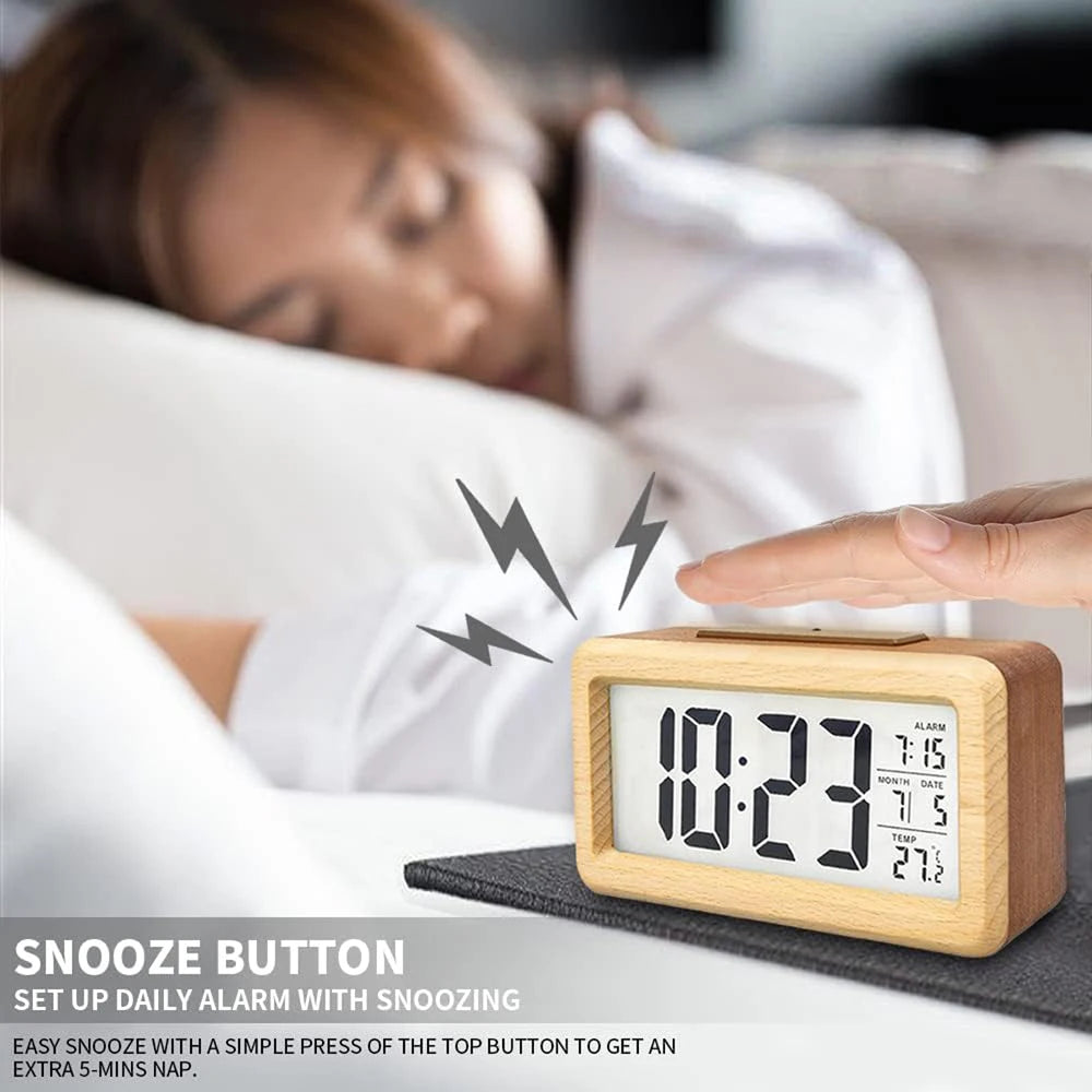 A hand is pressing the snooze button on a wooden digital alarm clock used for daily alarms with snoozing.