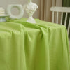 A lime green classic cotton rectangle tablecloth draped on a table with a white sculpted figure.