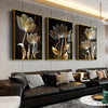 A set of three abstract flower canvas wall art pieces featuring golden and black tones displayed on a modern gray wall.