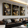 A set of three abstract flower canvas wall art pieces featuring golden and silver tones displayed on a modern gray wall above