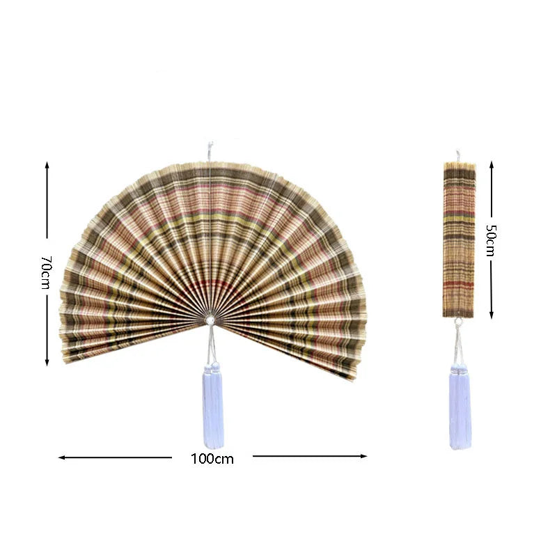Handwoven bamboo wall fan decor featuring a pleated design and a tassel.