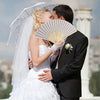 A bride and groom embracing, with the bride holding a folding fan in her hand.