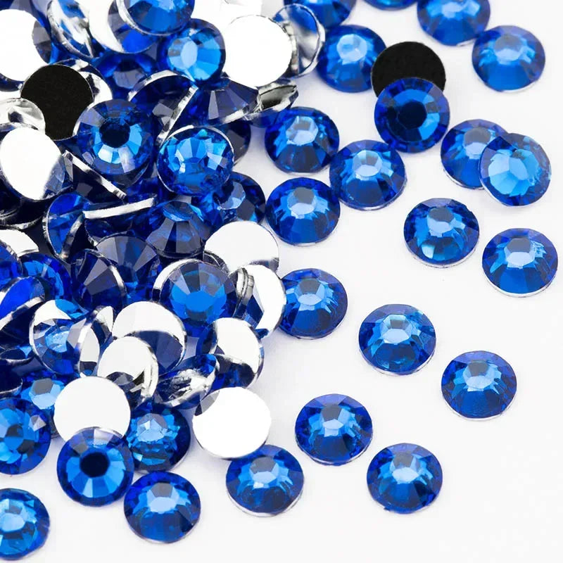 A close-up view of numerous round blue resin rhinestones scattered on a white background.