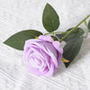 A single light purple artificial rose with green leaves on a white textured background.