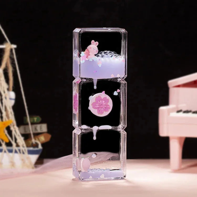A clear glass hourglass filled with purple liquid sand and pink panda shapes, used as a desk decor timer.