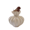 A minimalist ceramic vase in off-white color with a fluted shape holding dried brown floral elements.