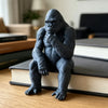 A dark gray 3D-printed gorilla figurine sitting on a stack of books.