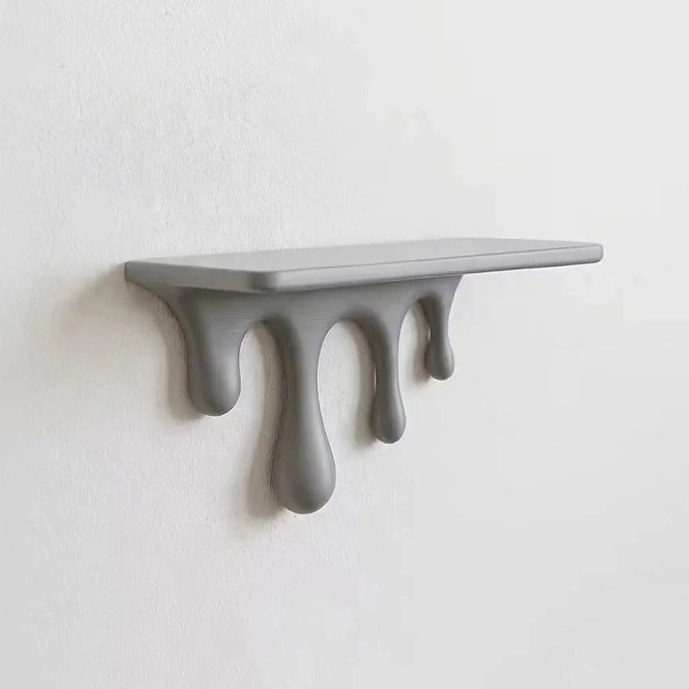 A gray drip floating shelf with three sculpted drops mounted on a white wall.