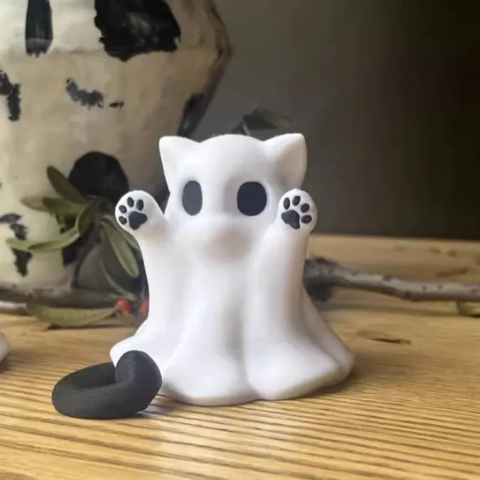 Weiße Keramikfigur einer Geisterkatze mit schwarzen Pfoten auf einer Holzoberfläche.