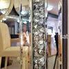A vertical silver crystal beveled wall mirror with a textured surface reflecting an interior space.