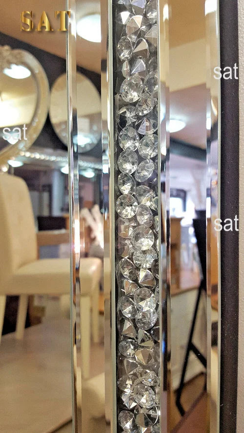 A vertical silver crystal beveled wall mirror with a textured surface reflecting an interior space.