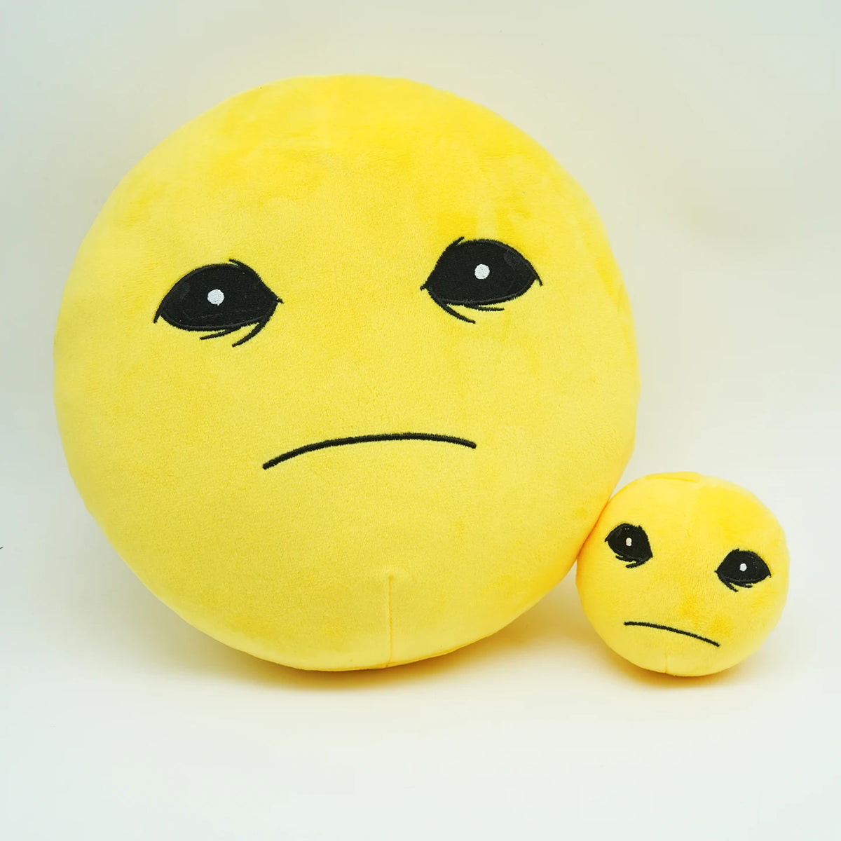 A yellow plush doll resembling a distressed face with black eyes and a smaller version nearby.