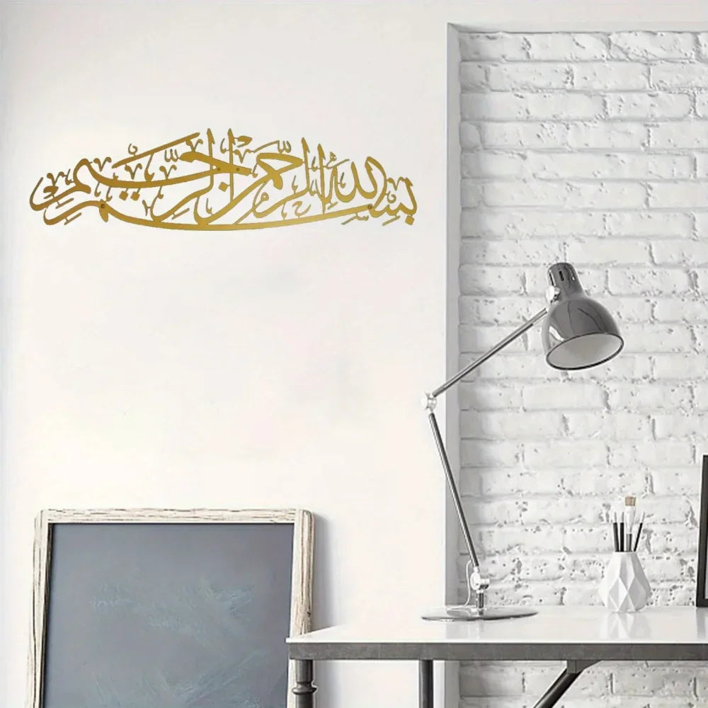 Gold Arabic calligraphy of Bismillah on a white wall above a desk.