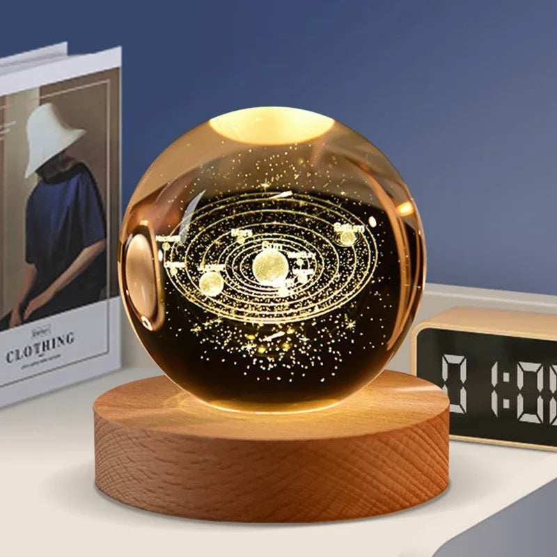 A glowing crystal ball decoration with a dark background and golden laser engraved patterns resting on a wooden base.