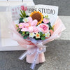 A bouquet of handmade crochet flowers in pink, yellow, and white arranged in a paper wrapping.