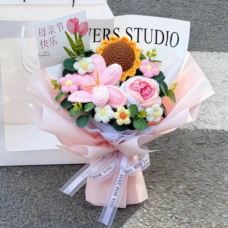 A bouquet of handmade crochet flowers in pink, yellow, and white arranged in a paper wrapping.