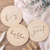 A set of natural wood plaques with script text saying It's a boy and It's a girl for gender reveal